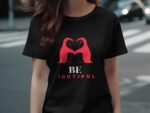 A woman wearing a black t-shirt featuring two red birds forming a heart shape, with the text "BE YOUTHFUL" below.