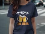 A person wearing a navy blue t-shirt with the text "I'M ONLY HERE FOR THE BEER" and two beer mugs graphic.