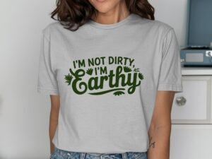 Woman wearing a light gray t-shirt with green text that reads "I'm not dirty, I'm Earthy." Background features furniture.