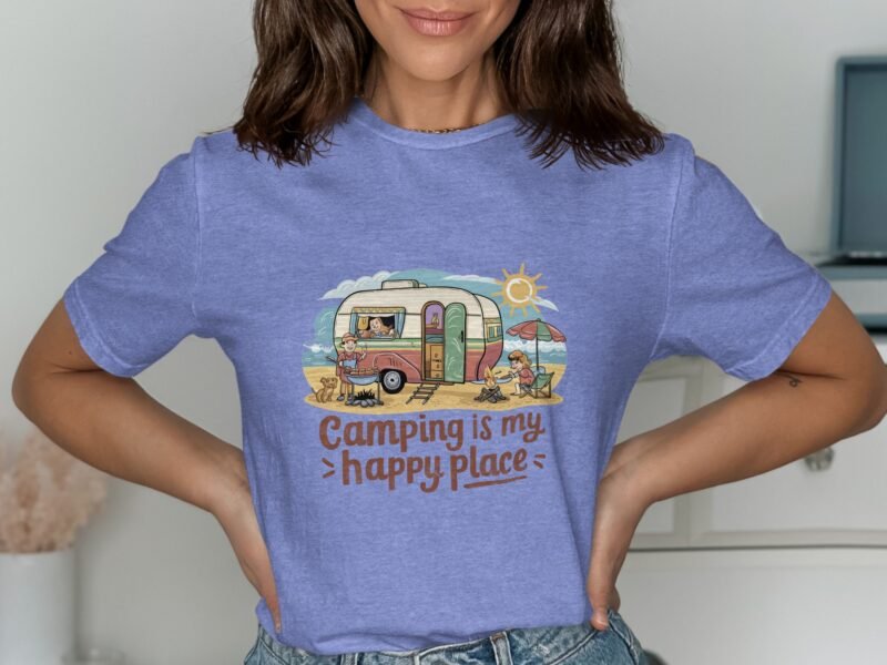 Woman wearing a blue t-shirt with a camping-themed design featuring a vintage camper, sun, and the text "Camping is my happy place."