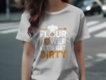 A woman wearing a light gray t-shirt with the text "FLOUR POWER - Let's Get DIRTY" in bold, playful fonts.