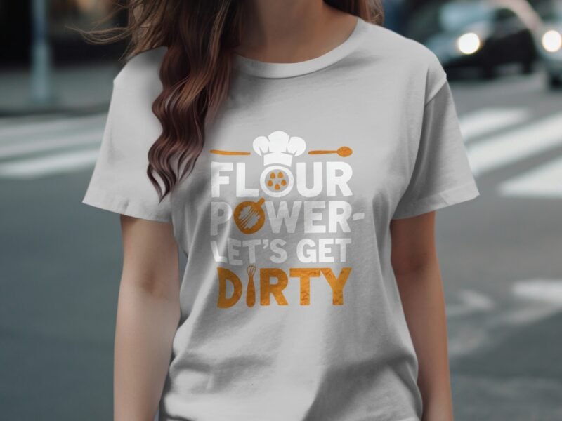 A woman wearing a light gray t-shirt with the text "FLOUR POWER - Let's Get DIRTY" in bold, playful fonts.