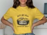 Woman wearing a yellow t-shirt with a camper graphic and the text "Let's Get Lost Adventure Awaits."