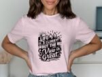 A woman in a pink t-shirt with a black graphic that says, "Life is a climb but the view is great."