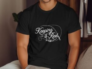 A man in a black t-shirt featuring the phrase "Keeping it Reel" with a fishing rod and fish graphic.