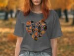 Woman wearing a gray Halloween-themed t-shirt with orange illustrations, standing in an autumn park with yellow foliage.