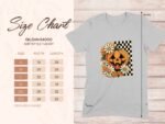 Size chart for Gildan 64000 softstyle T-shirt with floral and pumpkin graphic on a light grey fabric background.