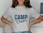 A woman wearing a gray t-shirt with "CAMP Crew" printed in blue, standing with her hands on her hips.