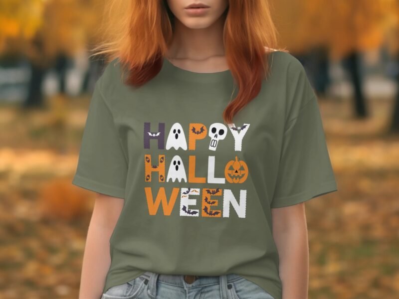Person wearing a green "Happy Halloween" t-shirt with spooky graphics, surrounded by autumn foliage.