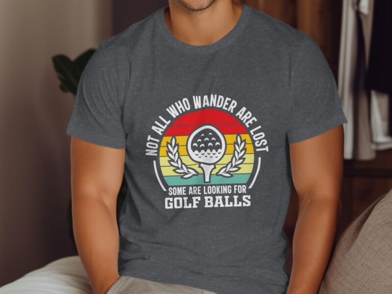 A man in a gray t-shirt with a graphic saying, "Not all who wander are lost, some are looking for golf balls."