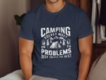 A person wearing a navy blue t-shirt with a camping-themed graphic and text that reads "Camping solves most problems."
