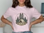 Woman wearing a pink t-shirt with a camp-themed graphic featuring trees and a tent, labeled "CAMP CREW."