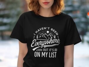 A woman with red hair wearing a black t-shirt featuring the phrase “I haven’t been everywhere but it’s on my list.”