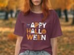 A person with long red hair wears a maroon t-shirt that reads "Happy Halloween" in colorful, spooky letters.