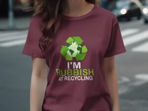 Woman wearing a maroon shirt with a recycling graphic and the text "I'M RUBBISH AT RECYCLING." Background of city street.