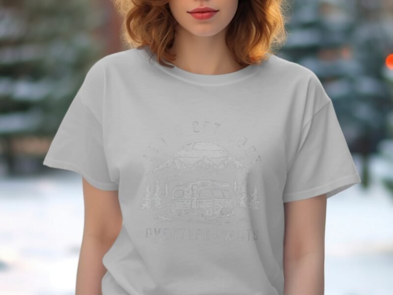 Woman wearing a light gray t-shirt with an outdoor adventure-themed graphic in a snowy setting.
