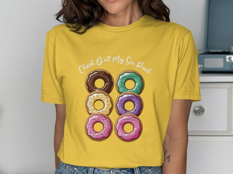 Person wearing a yellow shirt with a graphic of six colorful donuts and the text "Check Out My Six Pack."