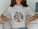 A woman in a light gray t-shirt displays text about life being better around a campfire, with tree and fire illustrations.