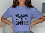 A woman wearing a light purple t-shirt with the text "Cocktails & Campfires" in black letters.