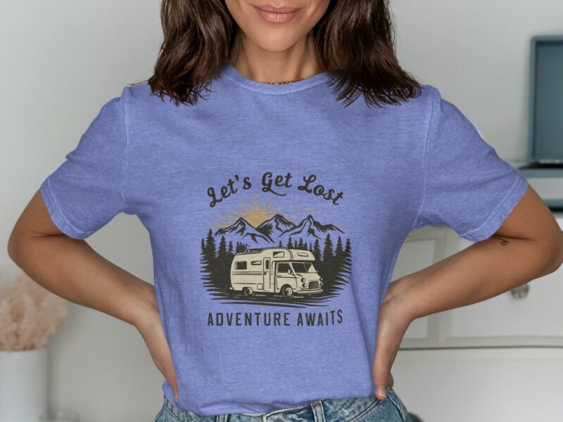 A woman in a blue t-shirt with a camper and mountains design, text reads "Let's Get Lost Adventure Awaits."