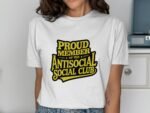 A woman wears a white t-shirt with "PROUD MEMBER OF THE ANTISOCIAL SOCIAL CLUB" printed in bold black and yellow letters.