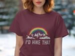 A woman wearing a maroon t-shirt with a rainbow and mountain graphic, featuring the text "I’d Hike That".