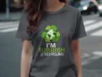 A person wearing a gray t-shirt featuring a recycling symbol and the text "I'm Rubbish at Recycling."
