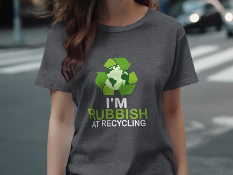 A person wearing a gray t-shirt featuring a recycling symbol and the text "I'm Rubbish at Recycling."