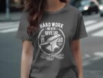 A person wearing a gray t-shirt with the text "HARD WORK NEVER GIVE UP" and an anvil graphic, standing on a street.