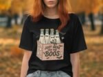 A woman with red hair wears a black t-shirt featuring a graphic of beer bottles and the text "Just Here for the Boos."