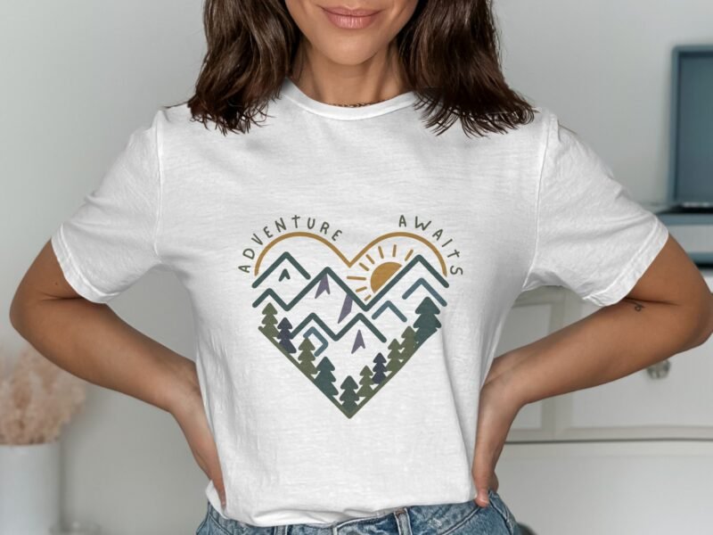 Woman wearing a white t-shirt with a heart-shaped mountain graphic and the text "Adventure Awaits."