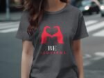 A woman wearing a gray t-shirt with a red heart design and the text "BE YOUTIFUL" in white and red.