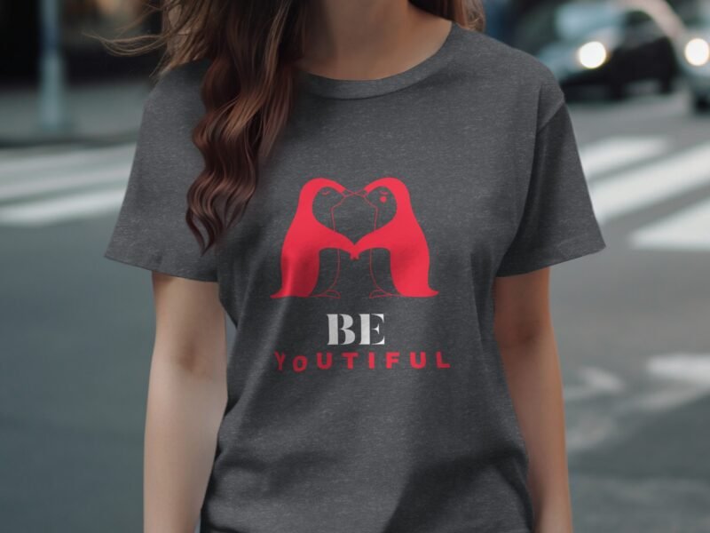 A woman wearing a gray t-shirt with a red heart design and the text "BE YOUTIFUL" in white and red.