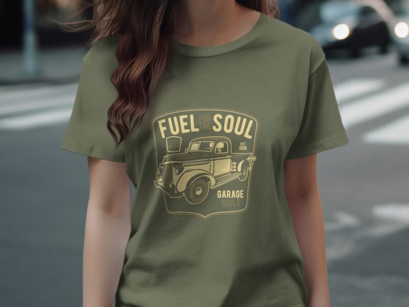 Woman wearing an olive green t-shirt with a vintage truck graphic and the text "Fuel for the Soul, Garage Built."