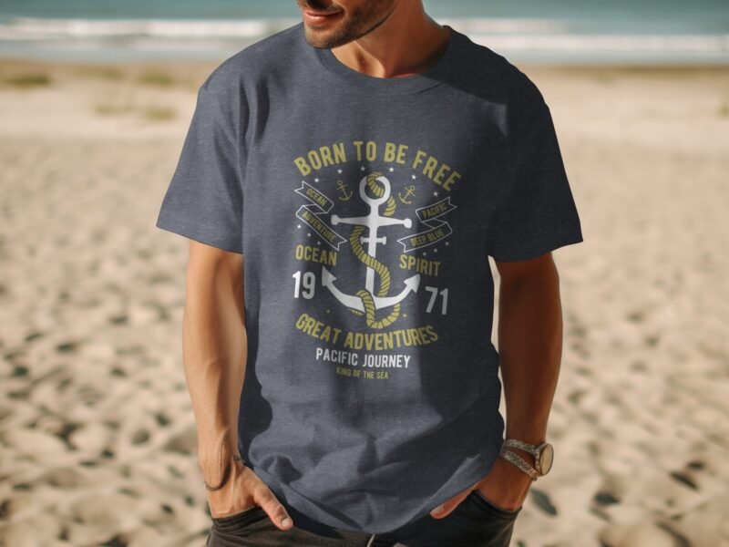 A man wearing a navy blue t-shirt with an anchor graphic and the text "Born to Be Free" stands on a sandy beach.