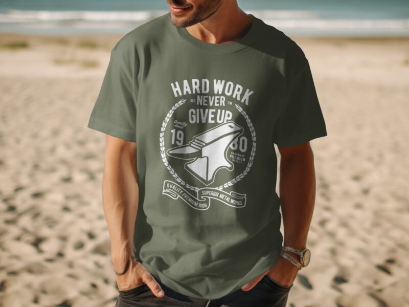 A man wears an olive green t-shirt with a white graphic design featuring an anvil and the text "Hard Work Never Give Up."