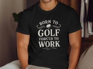 Man wearing a black t-shirt with white text: "BORN TO GOLF FORCED TO WORK," sitting in a cozy room.