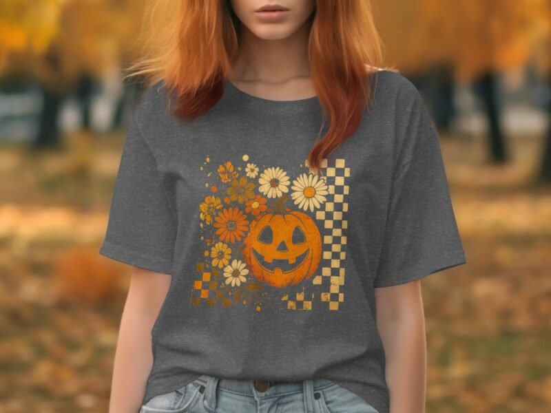 A woman with red hair wears a gray t-shirt featuring a pumpkin and floral design, set against an autumn background.