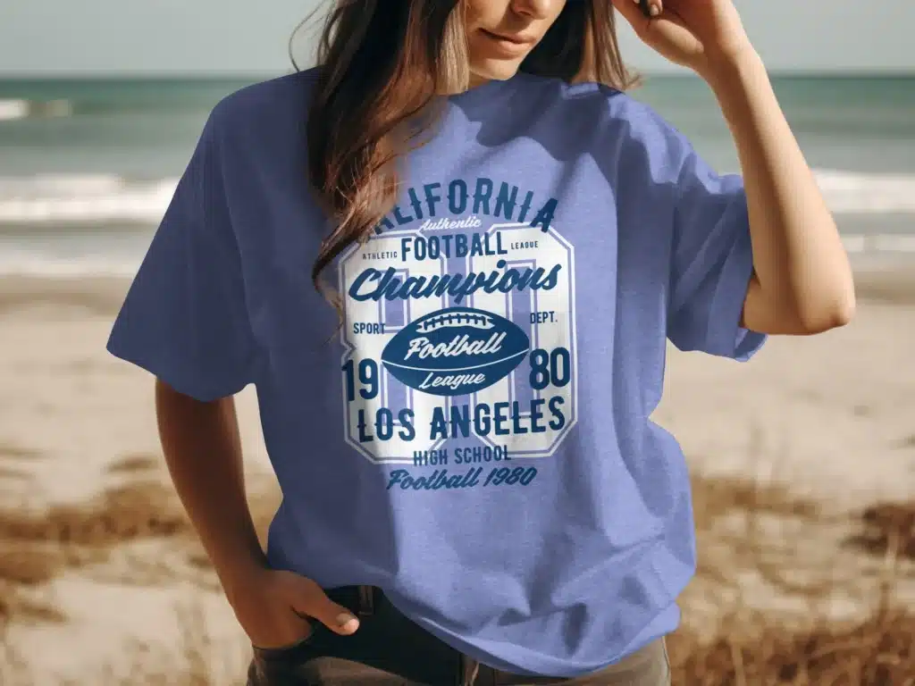 A woman on the beach wearing a t-shirt with an american football in the centre
