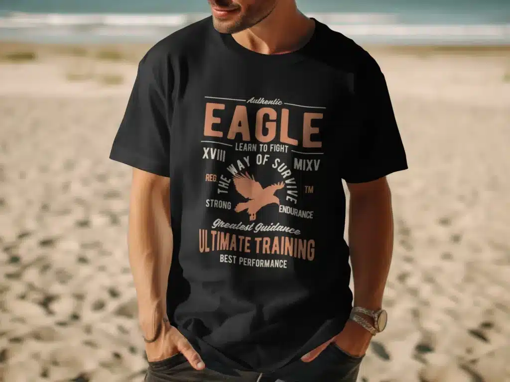 a man on the beach wearing a black t-shirt with an eagle in the centre