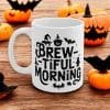 A mug with the words Brewtiful Morning written in black and surrounded by ghoulish creatures