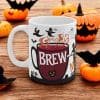 Mug with the word Brew on it and witches hats and ghouls flying around