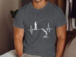 A person in a gray shirt with a fishing graphic, featuring a heartbeat line and a fish jumping from water.