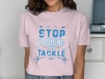Woman wearing a light pink t-shirt with the text "STOP LOOKING AT MY TACKLE" in blue graphic letters.