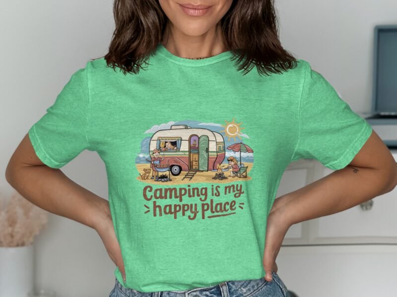 A woman in a green t-shirt featuring a camping graphic with a camper, sun, and the text "Camping is my happy place."