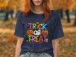 A person wearing a navy t-shirt featuring colorful "Trick or Treat" Halloween graphics with pumpkins and a ghost.