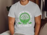 A person wearing a white t-shirt with green golf-themed text: "GOLF KID LIKE REGULAR KID BUT COOLER."