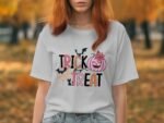 A woman with red hair wears a light gray t-shirt featuring "TRICK or TREAT" with Halloween graphics against an autumn backdrop.