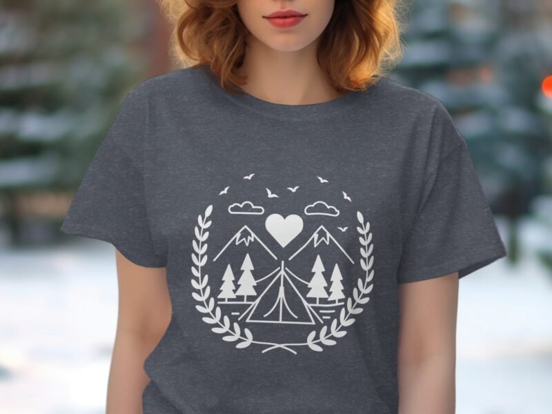 A woman models a charcoal gray t-shirt featuring a white graphic of mountains, trees, a tent, and a heart.
