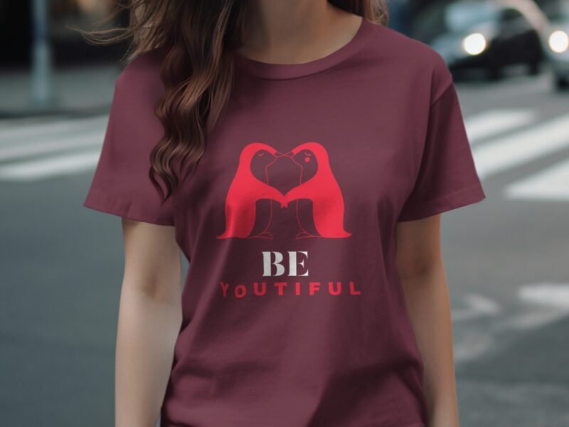 A person wearing a maroon t-shirt featuring a graphic of two figures and the text "BE YOUTIFUL" below.